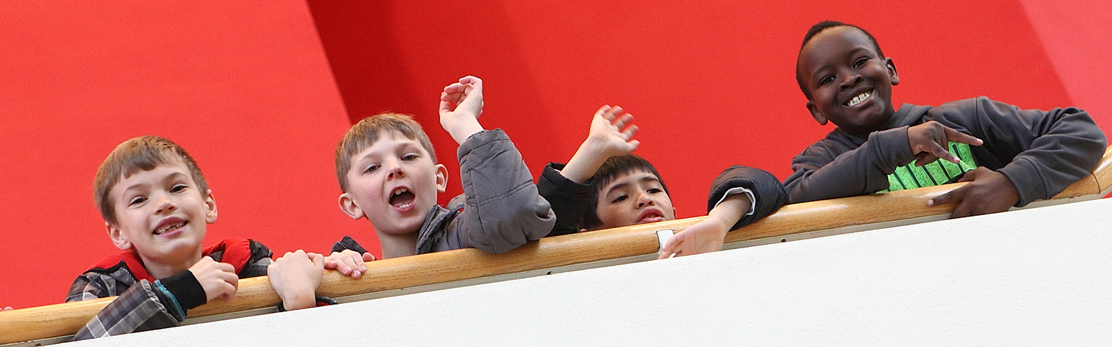 children waving down from lobby steps